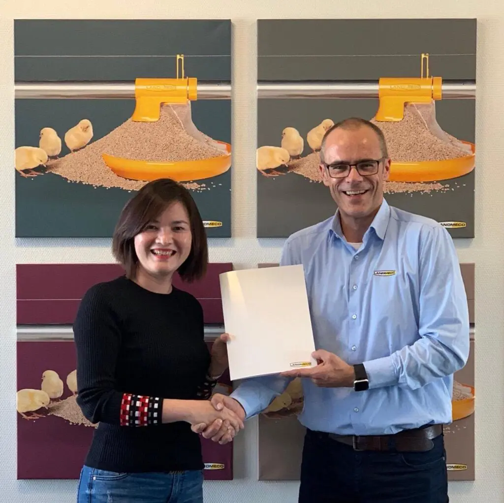 LANDMECO team members shaking hands in front of broiler feeding system art, representing poultry industry partnerships.