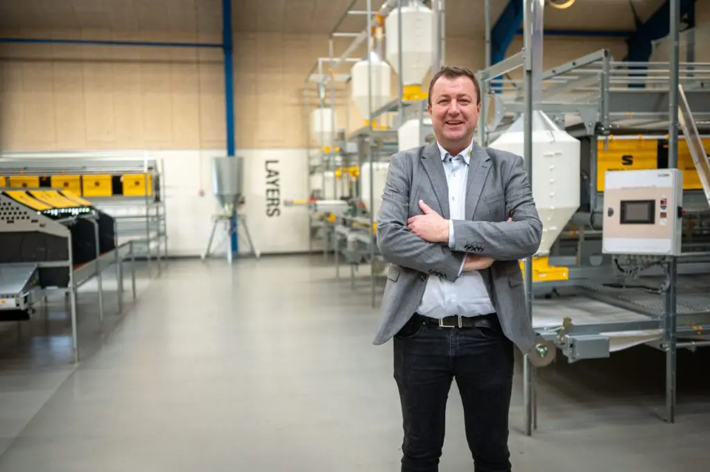 Anders Scaled of LANDMECO in a showroom featuring layer aviary systems for efficient cage-free egg production.