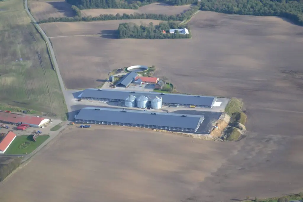Aerial view of large industrial poultry houses and feed silos on a Scandinavian farm facility.