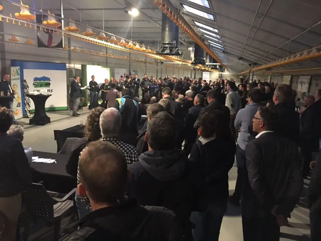 Crowd at a LANDMECO poultry event showcasing broiler pan feeding systems in a modern poultry house.