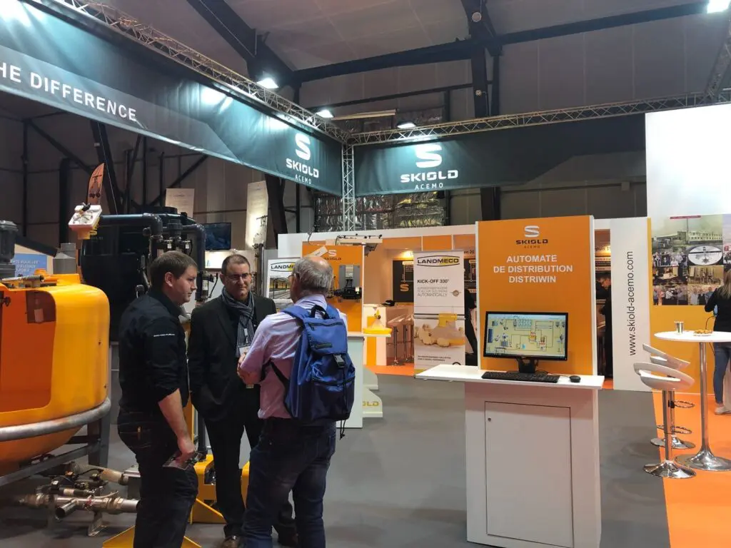 LANDMECO experts at a trade show discussing the Kick-off 330 broiler feeding system and poultry automation software.