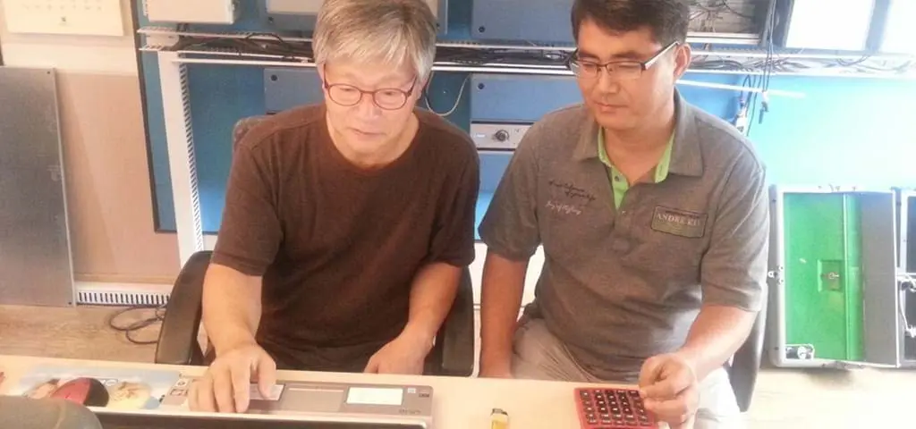 Chanho Park and Changhui Won from LANDMECO analyzing technical data on a laptop and calculator in a professional office.