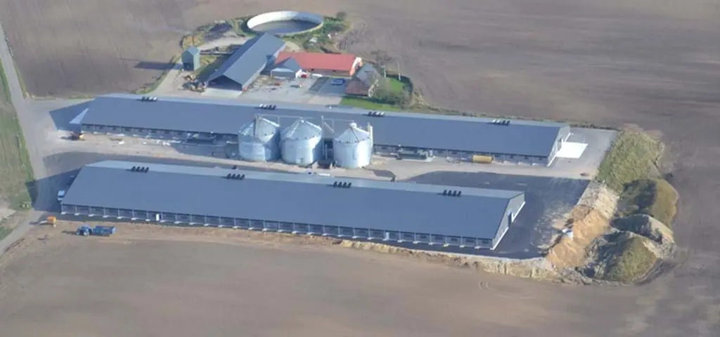 Aerial view of a large modern poultry farm featuring LANDMECO broiler equipment, silos, and automated systems.