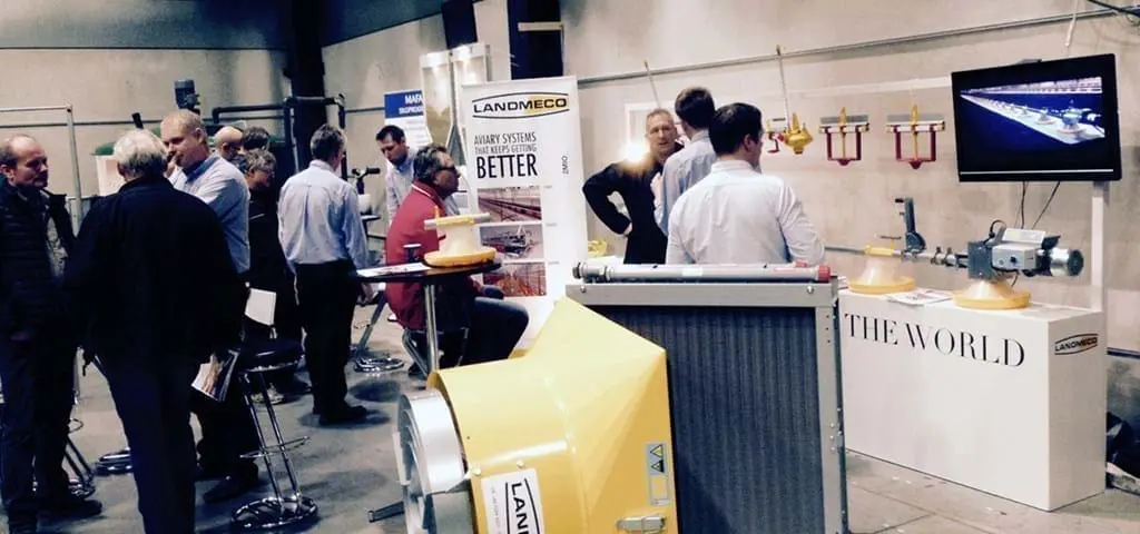 LANDMECO staff presenting poultry aviary and feeding systems at an industry exhibition booth.