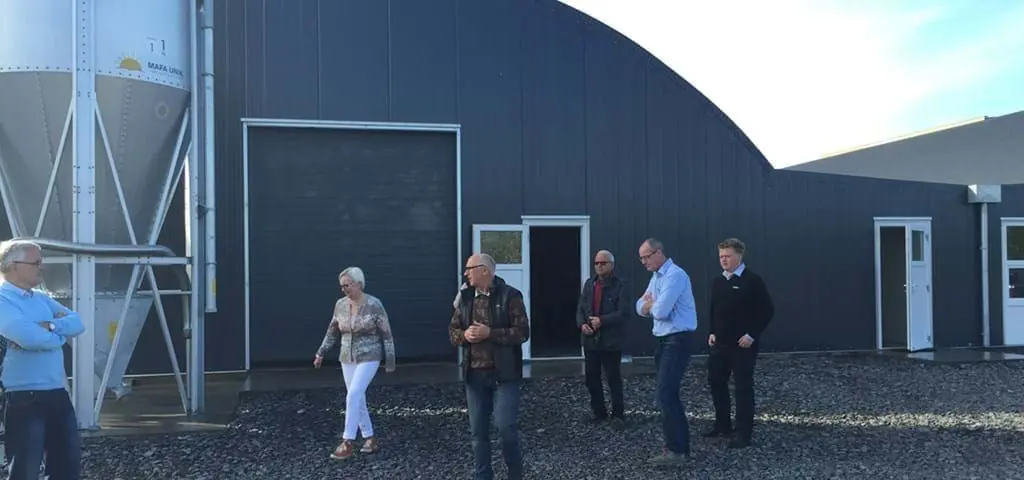 A group of professionals visiting a modern poultry house featuring LANDMECO automated feeding and silo systems.