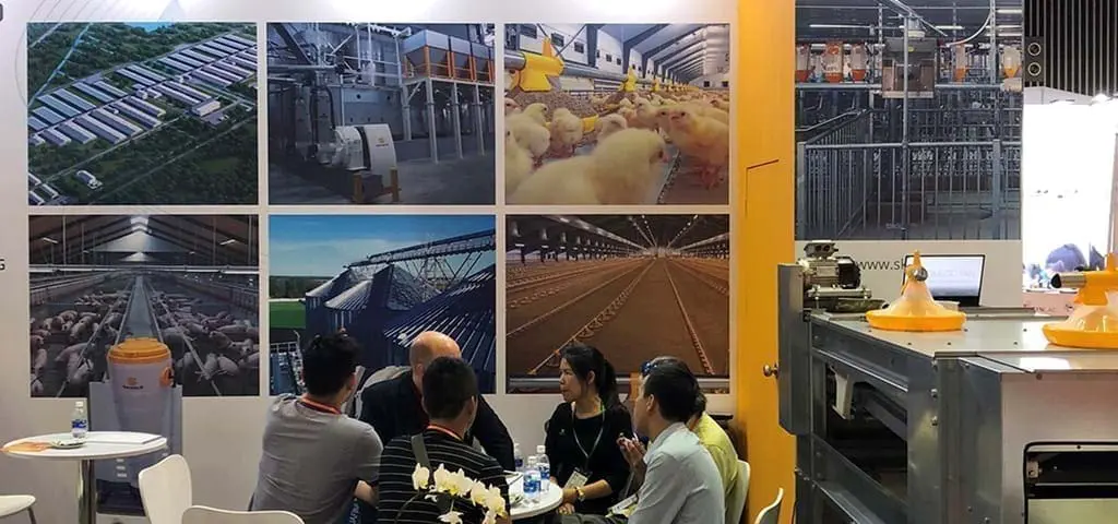 LANDMECO Vietstock booth showing poultry farming equipment, chicks, silos, and B2B consultations at a trade show.