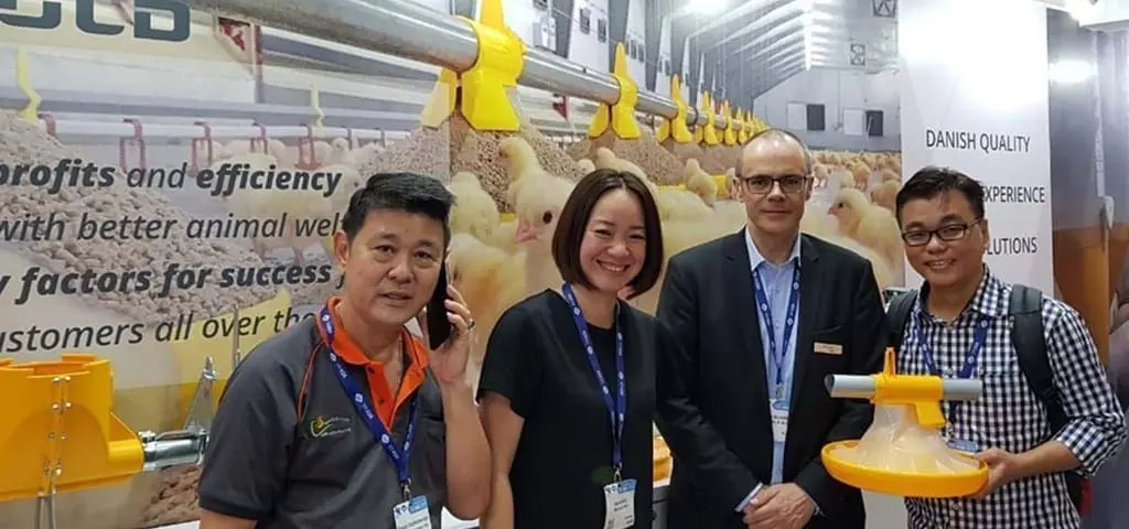 LANDMECO team at Vietstock showcasing yellow broiler pan feeding systems and Danish poultry equipment solutions.