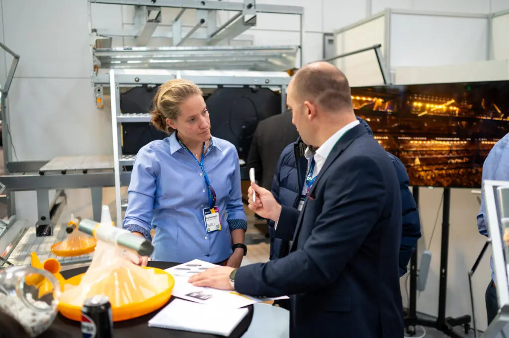 Angelika Jürgens of LANDMECO discusses poultry systems with a potential dealer at a trade fair.