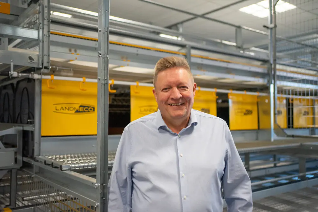 Tommy Høgedal Krogh, LANDMECO poultry specialist, standing in front of automated aviary systems.