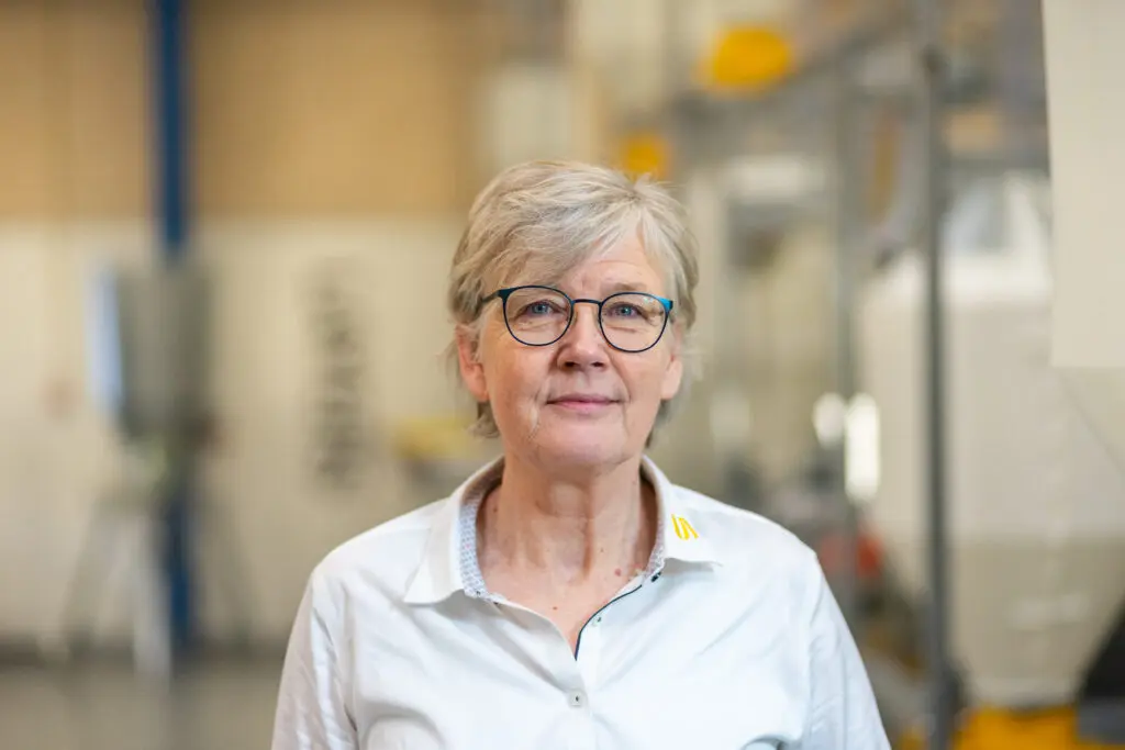 Portrait of Susanne Friis, LANDMECO Regional Sales Director, in a professional industrial poultry setting.