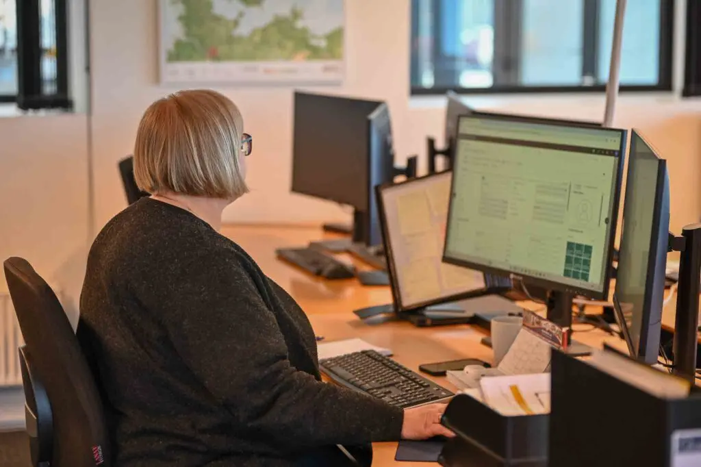 Medarbejder hos LANDMECO arbejder ved computer med økonomisk overblik og data i et moderne kontormiljø.