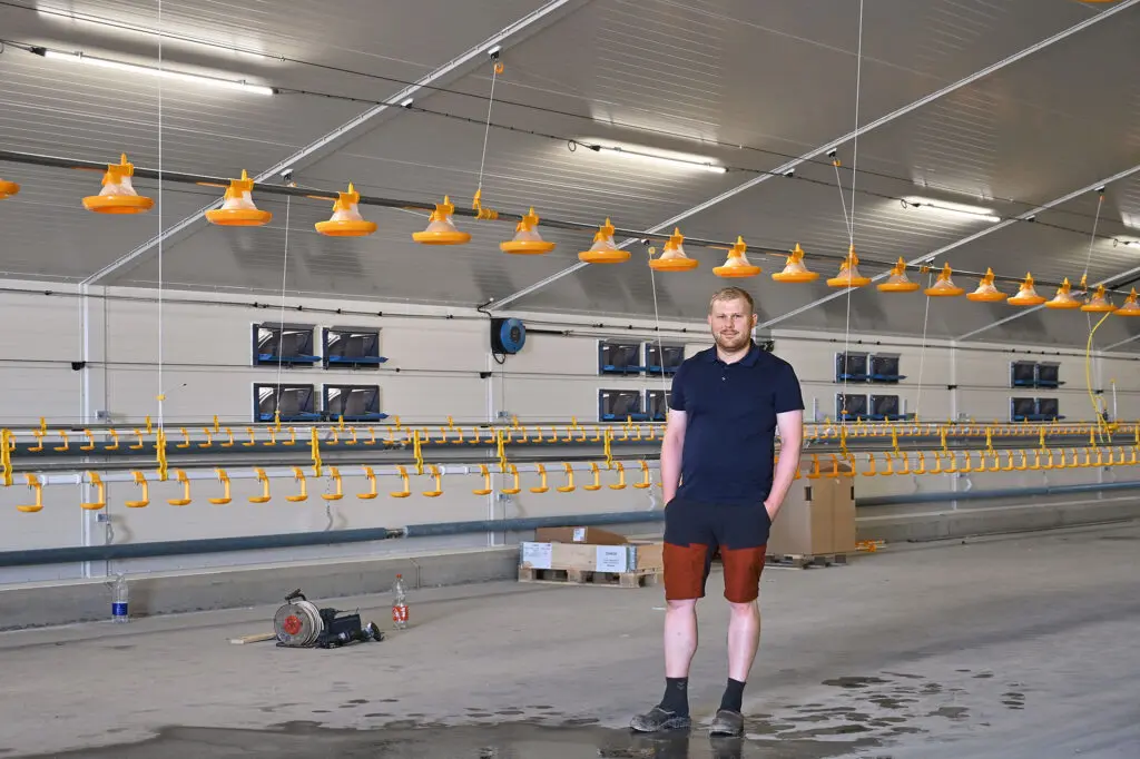 Mathias Højgaard står midt i sin nye 3.000 kvadratmeter store kyllingestald udstyret med gult LANDMECO-fodringsudstyr.