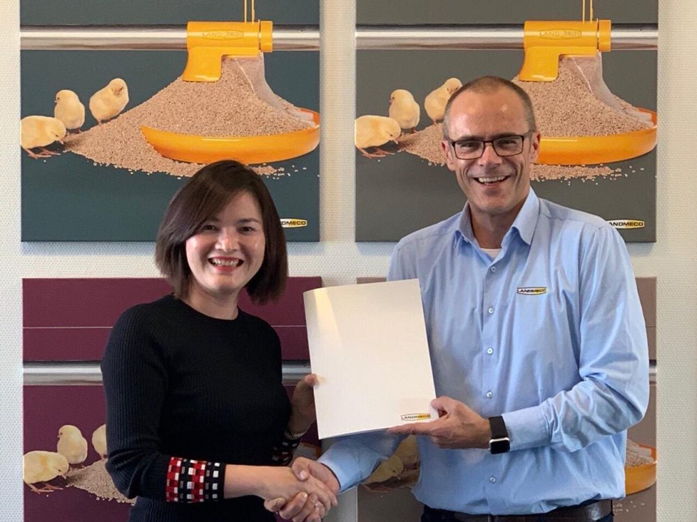 LANDMECO team members shaking hands in front of broiler feeding system art, representing poultry industry partnerships.