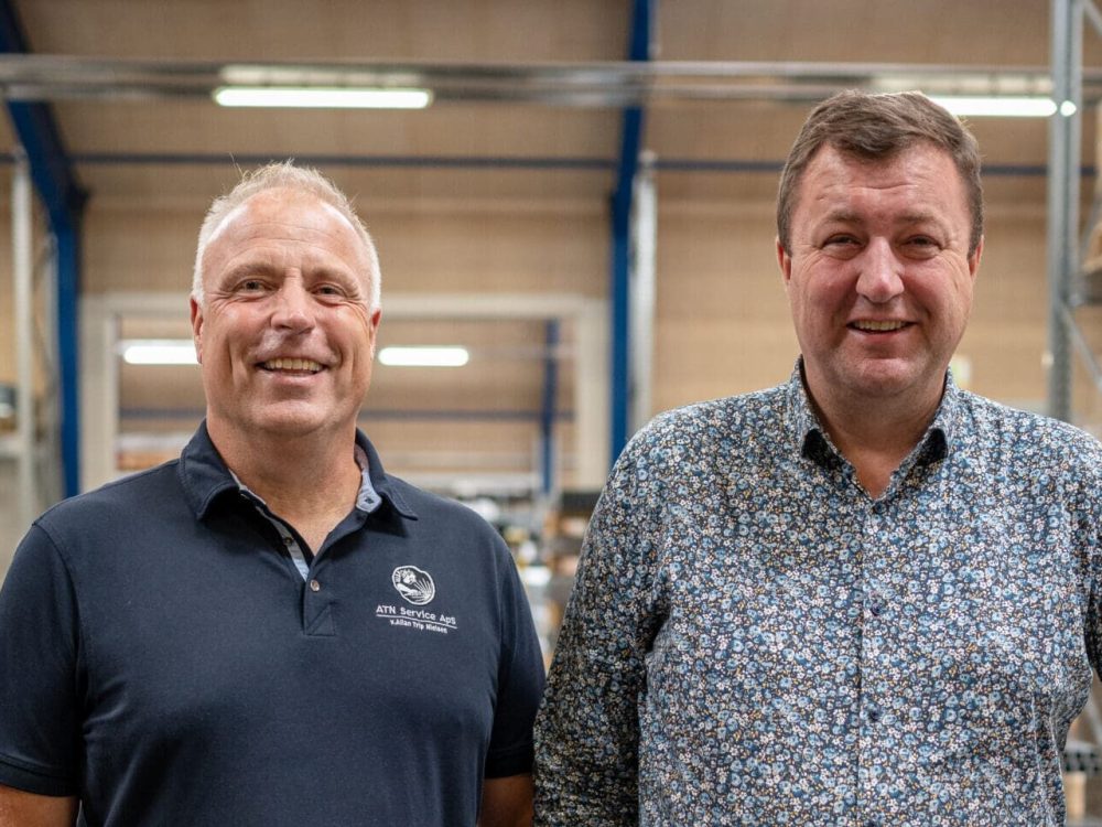 Mogens Hansen fra ATN Service og Anders Kristian Andersen fra LANDMECO smiler i en lagerhal.