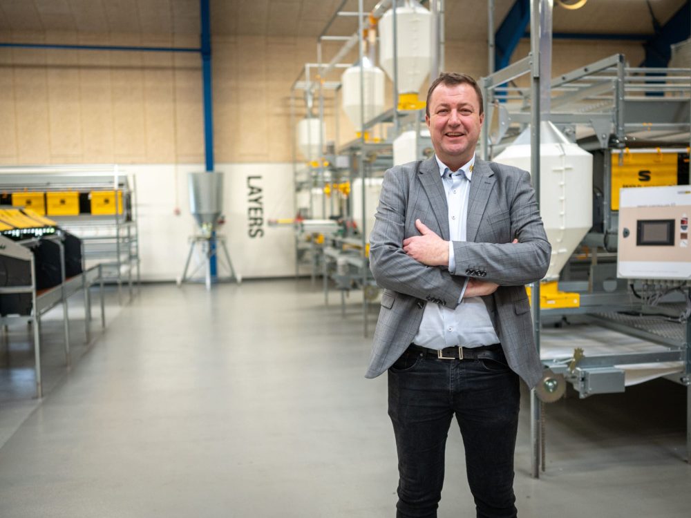Anders Scaled of LANDMECO in a showroom featuring layer aviary systems for efficient cage-free egg production.