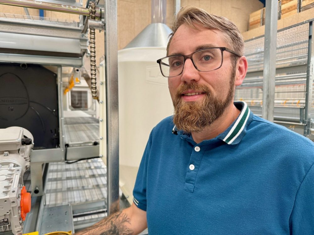 Benjamin Freise standing with LANDMECO poultry farming systems and automated equipment for egg production.