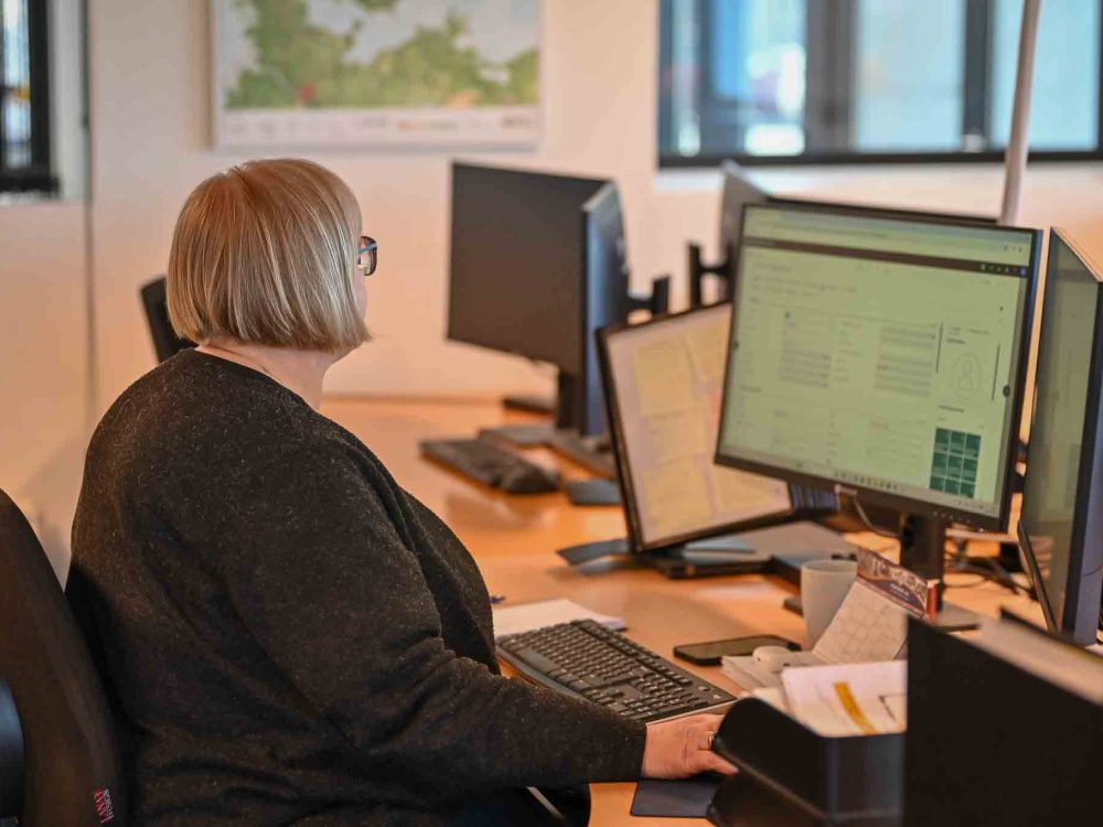 Medarbejder hos LANDMECO arbejder ved computer med økonomisk overblik og data i et moderne kontormiljø.