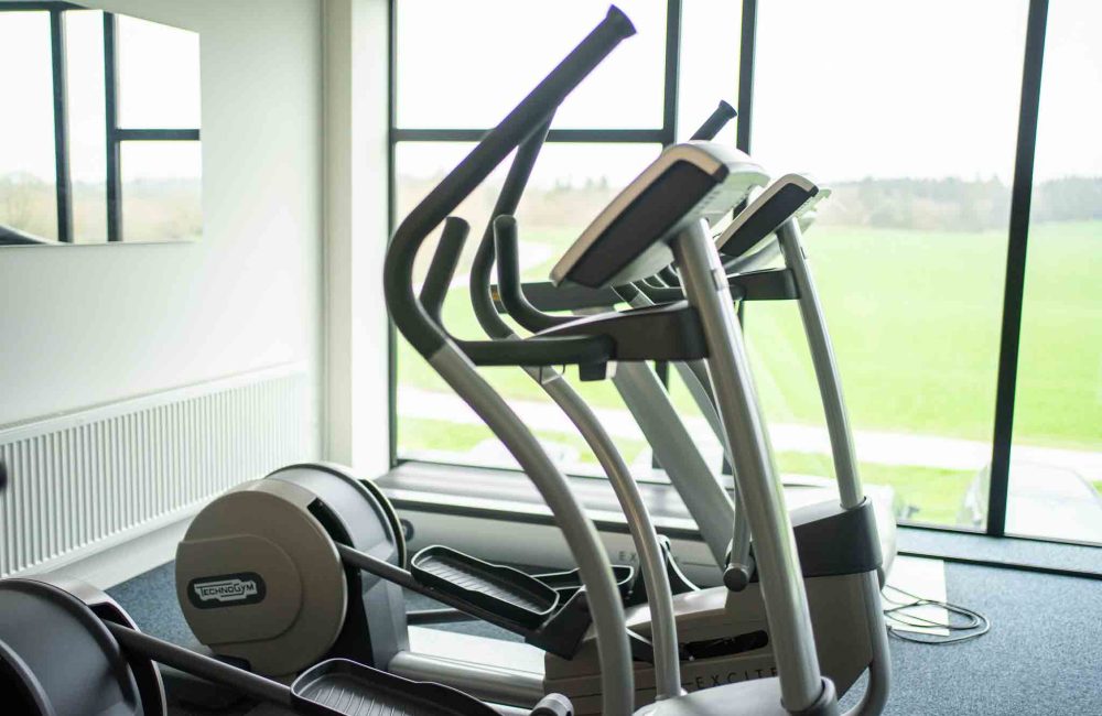 LANDMECO Employee Wellness & Social Responsibility Modern gym equipment for employees in a bright LANDMECO facility overlooking a scenic field in Ølgod.