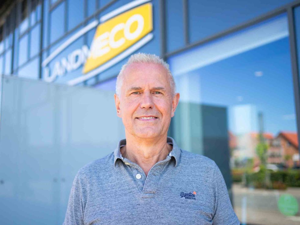Portrait of Ryan Zinglersen standing outdoors in front of a building with the Landmeco logo.