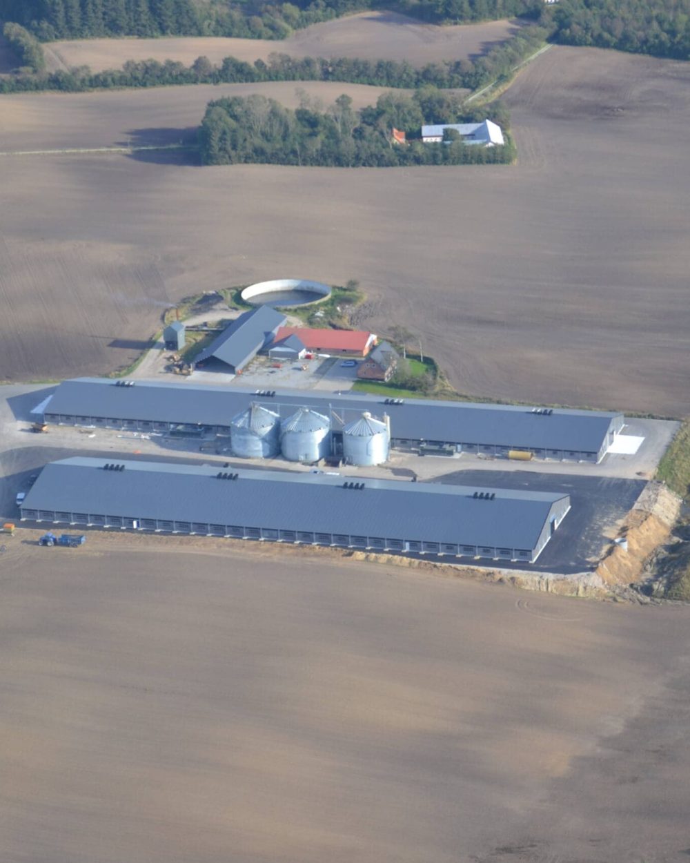 Aerial view of large industrial poultry houses and feed silos on a Scandinavian farm facility.