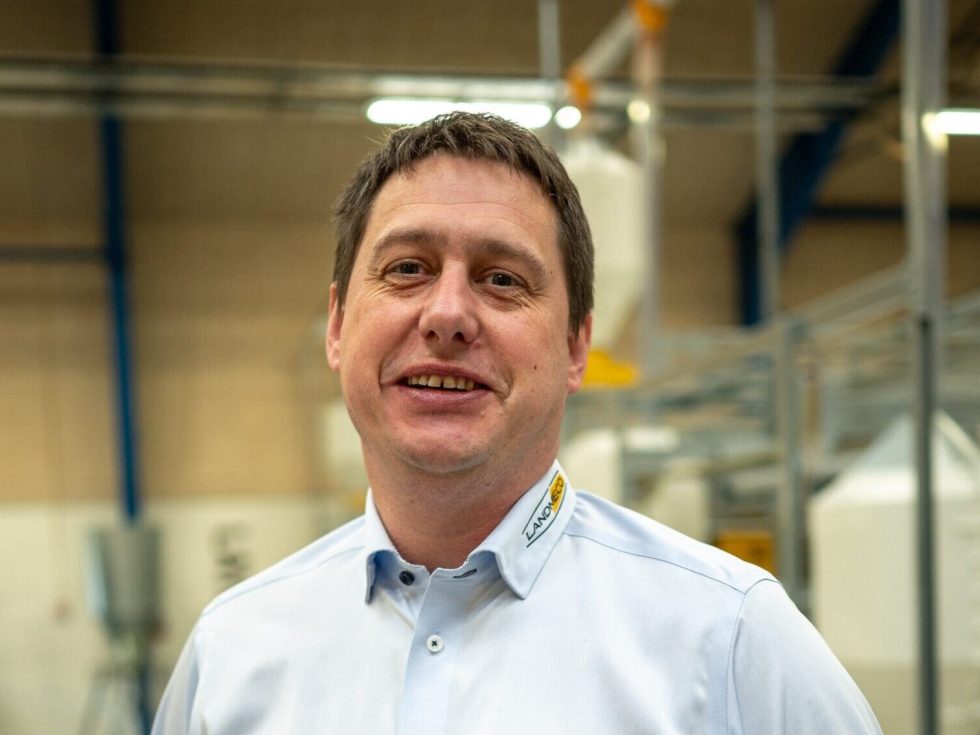 Portrait de Alex Dybdal en chemise LANDMECO dans une usine de matériel d'élevage avicole.