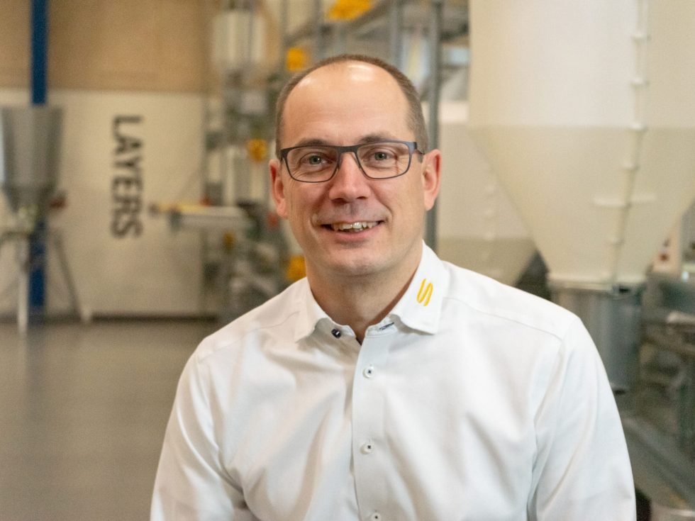 Portrait d'Alex Dybdal de LANDMECO devant un système pour poules pondeuses en environnement industriel.