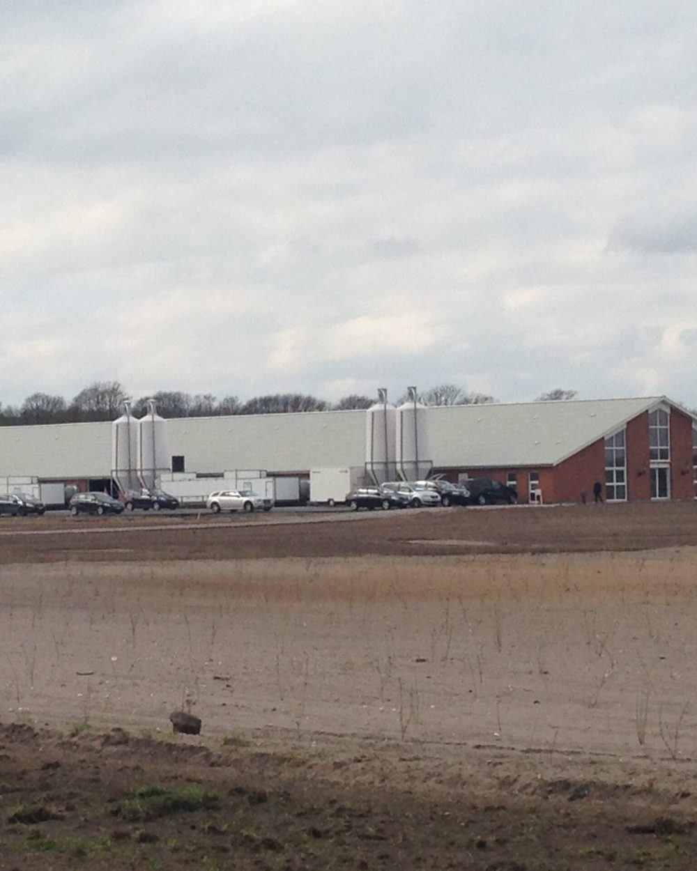 Large modern poultry house with feed silos and office section, showcasing integrated LANDMECO poultry equipment.