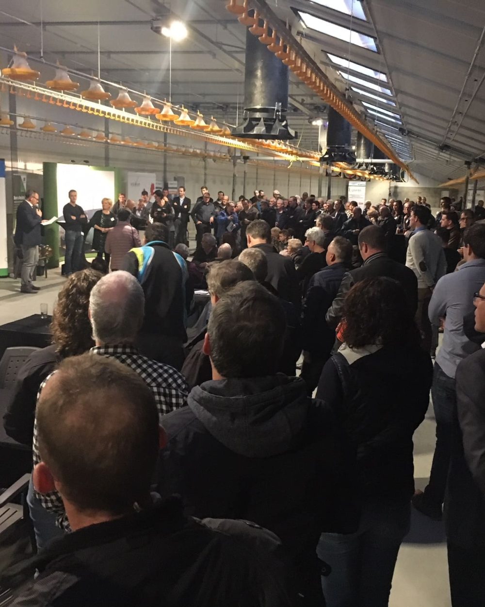 Crowd at a LANDMECO poultry event showcasing broiler pan feeding systems in a modern poultry house.