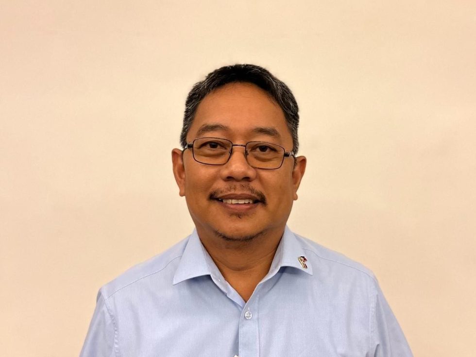 Professional headshot of Roland Grabador, LANDMECO team member, in a light blue shirt against a neutral background.