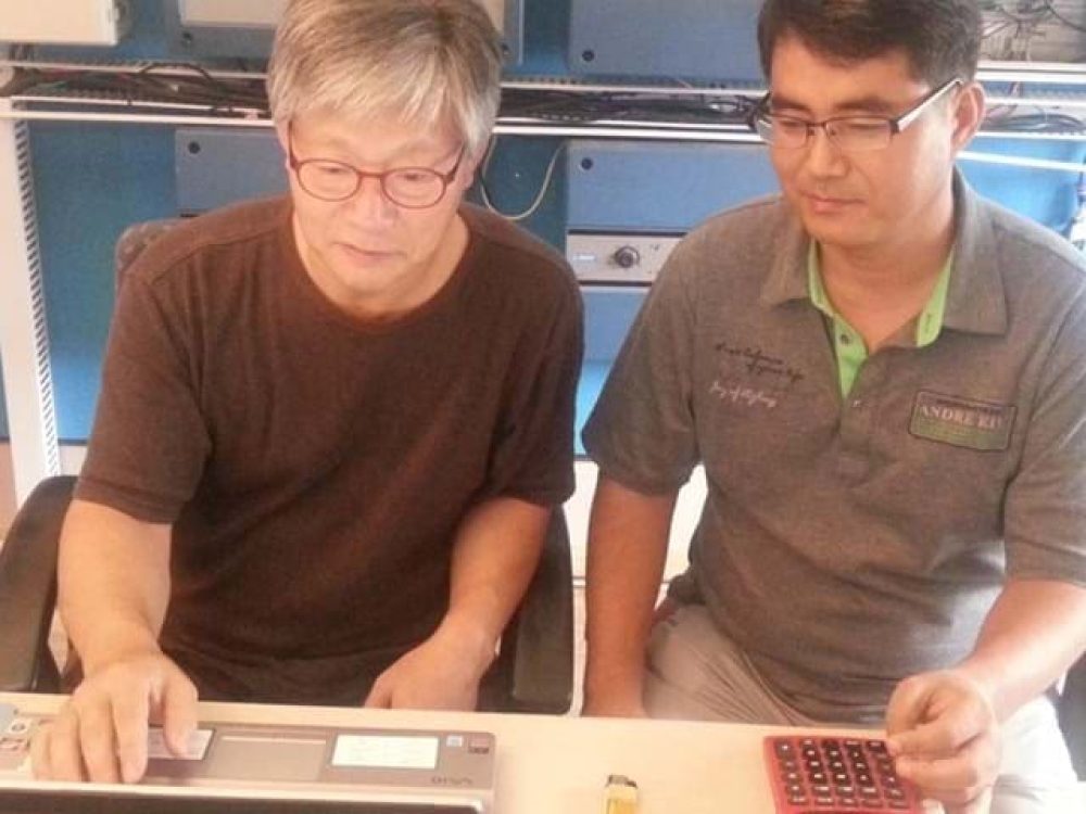 Chanho Park and Changhui Won from LANDMECO analyzing technical data on a laptop and calculator in a professional office.