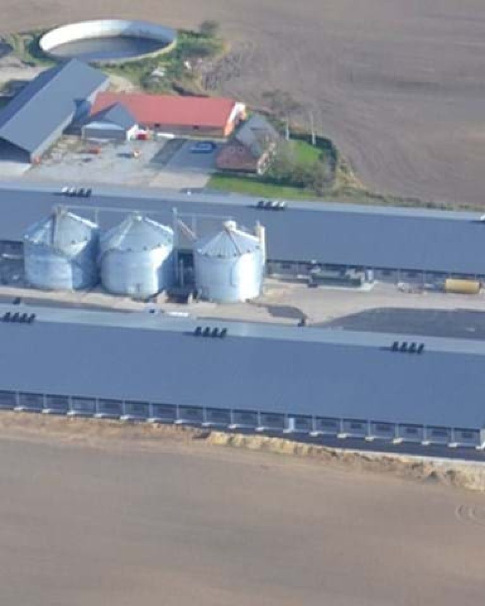 Aerial view of a large modern poultry farm featuring LANDMECO broiler equipment, silos, and automated systems.