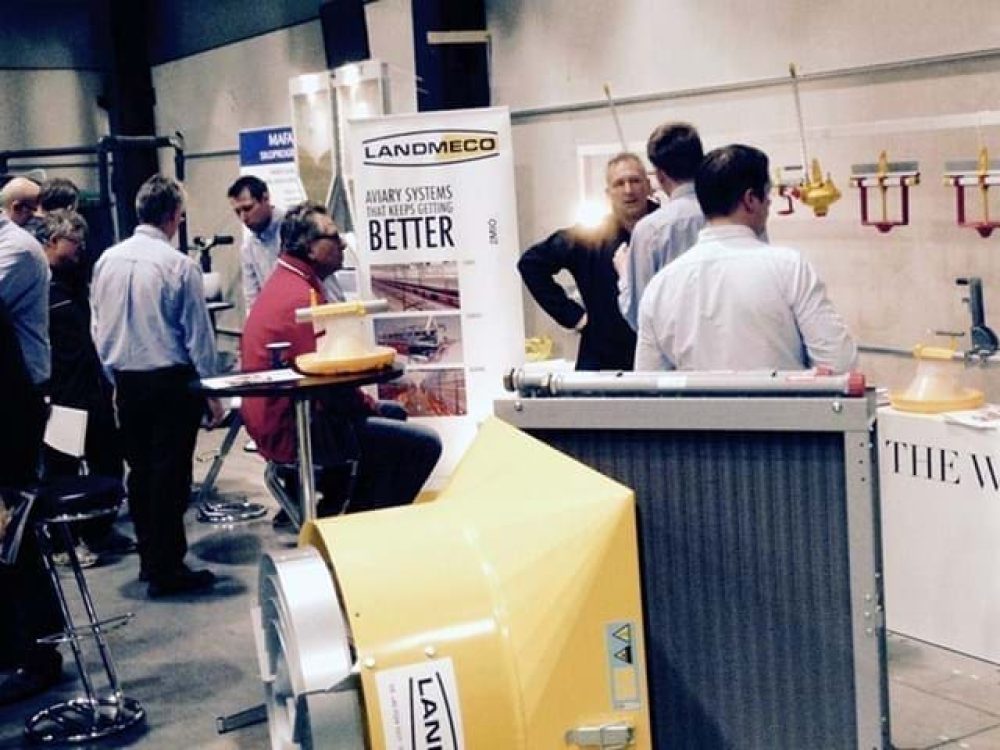 LANDMECO staff presenting poultry aviary and feeding systems at an industry exhibition booth.
