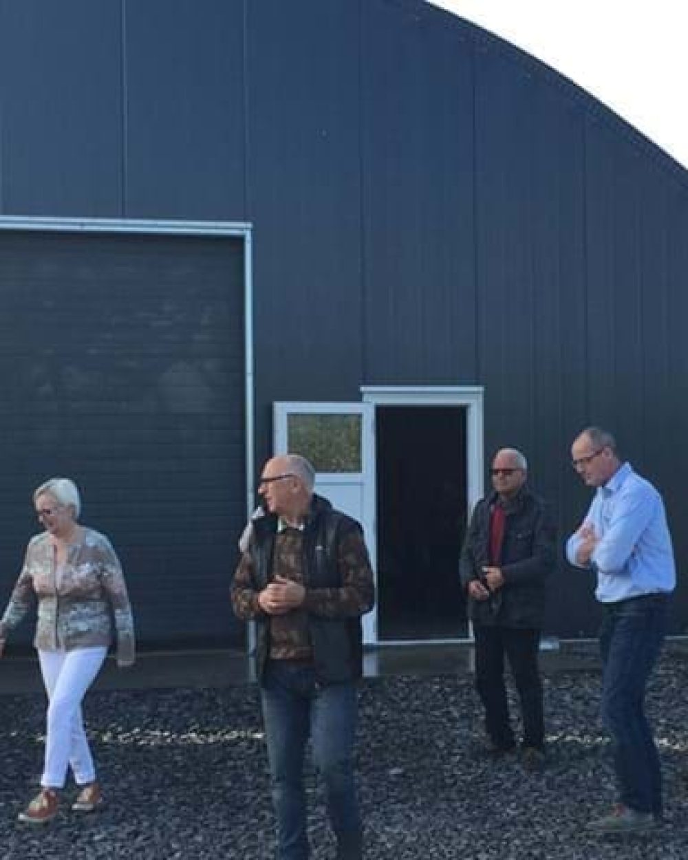 A group of professionals visiting a modern poultry house featuring LANDMECO automated feeding and silo systems.