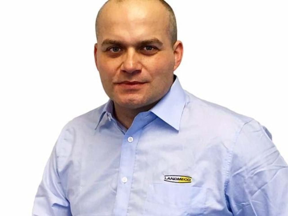 Tomasz, a professional from LANDMECO, wearing a branded light blue shirt against a white background.