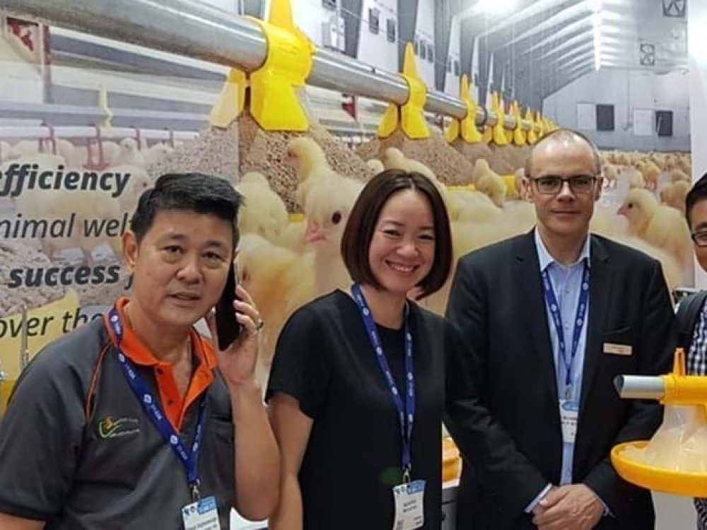 LANDMECO team at Vietstock showcasing yellow broiler pan feeding systems and Danish poultry equipment solutions.